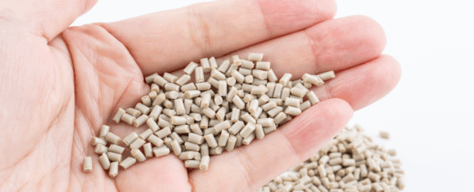 Hand holding recycled PEEK polymer pellets used in high-performance industrial manufacturing