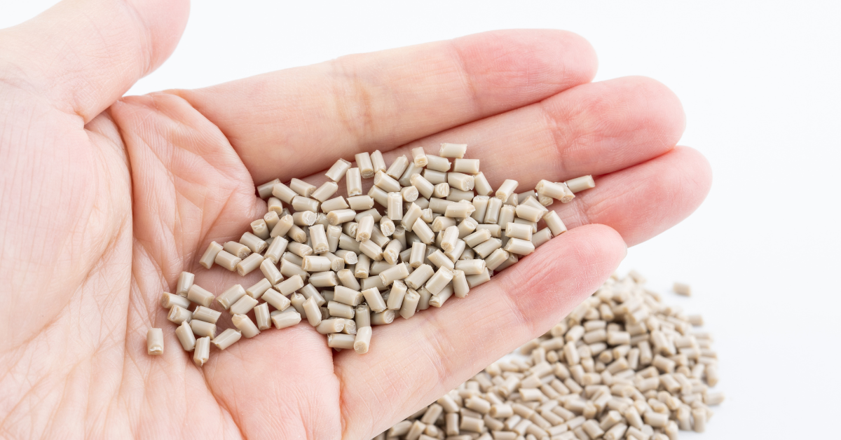 Hand holding recycled PEEK polymer pellets used in high-performance industrial manufacturing